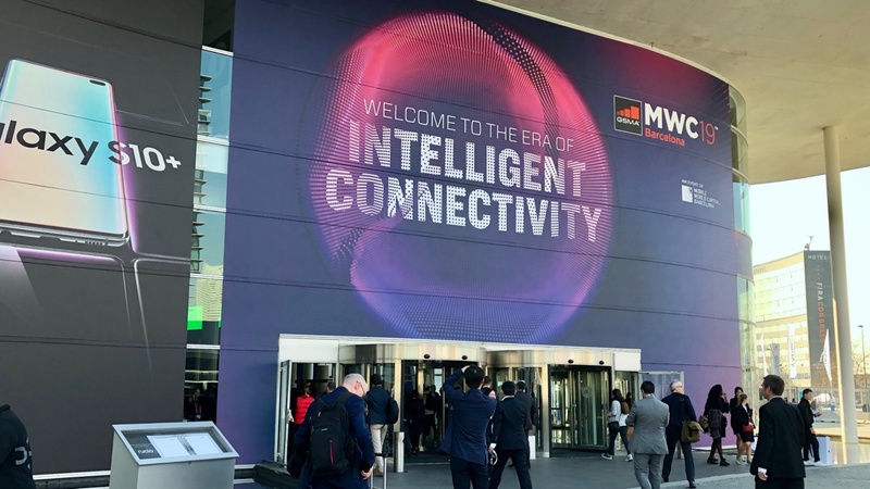 写真2：MWCでの一コマ。入口には2019年のテーマ“Intelligent Connectivity”の文字が見える
